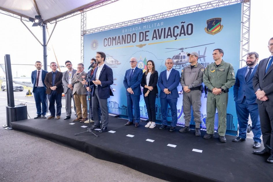 Foto mostra o governador Eduardo Leite discursando ao lado de outras autoridades e militares.