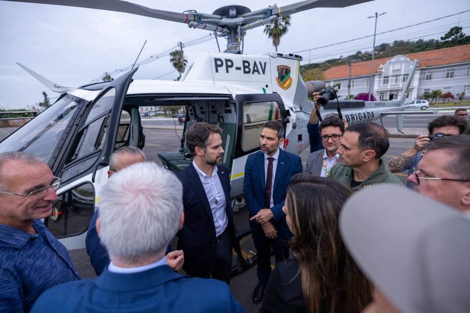 Foto mostra o governador Eduardo Leite em frente ao helicóptero com outras autoridades e militares.